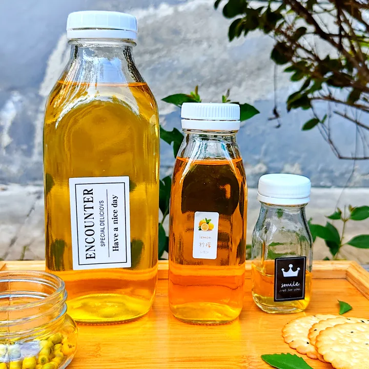 Clear glass juice bottles with printed labels in different capacities