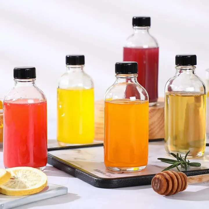 Glass bottles filled with juice beside lemon and honey dipper