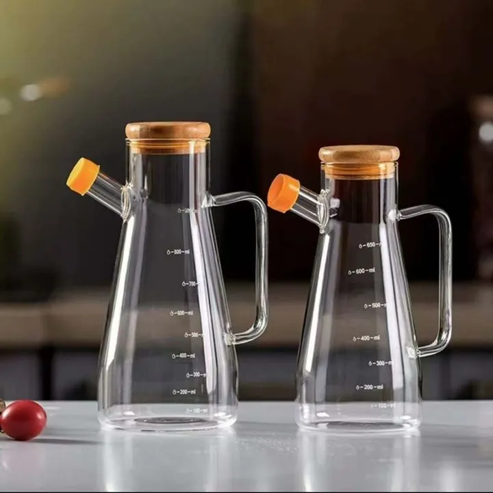 Deux pichets à condiments en verre gradués avec des couvercles en bois, dans un décor de cuisine