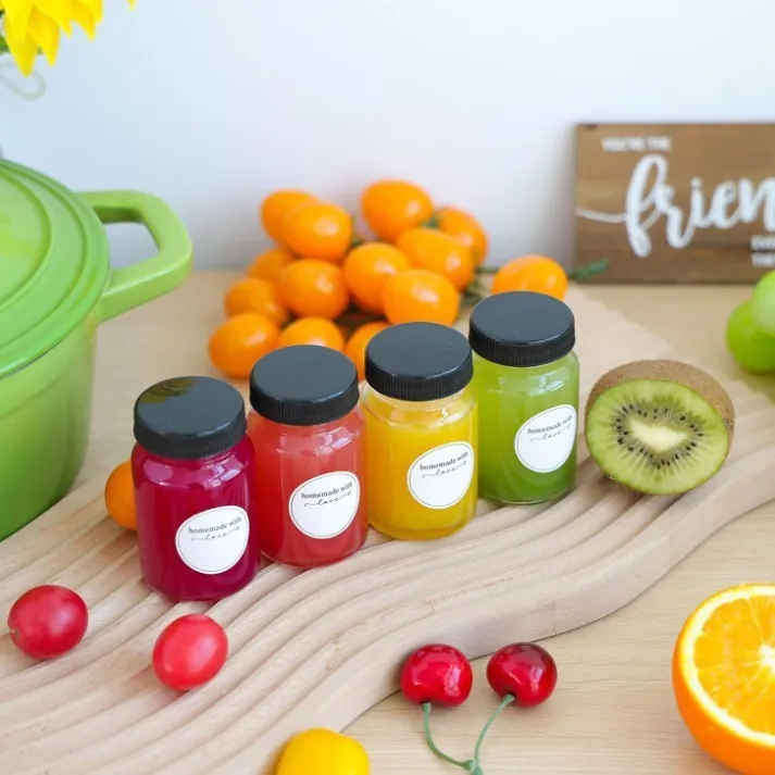 Labeled glass juice bottles displayed with fruit
