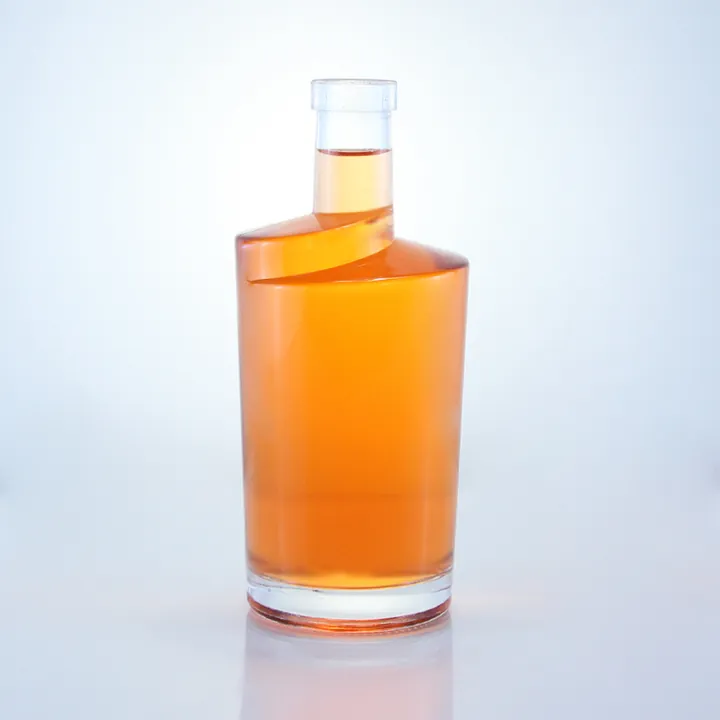 Slanted shoulder cylindrical liquor bottle filled with orange liquid