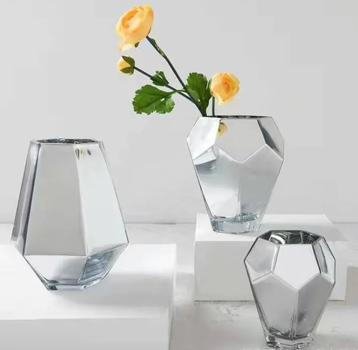 Drei verspiegelte geometrische Glasvasen mit Blumen