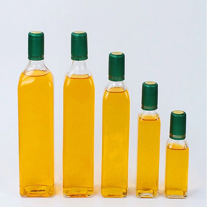Square olive oil bottles filled with yellow oil and green caps