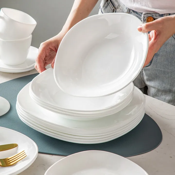 Une vaisselle en opale d'un blanc immaculé disposée sur la table à manger