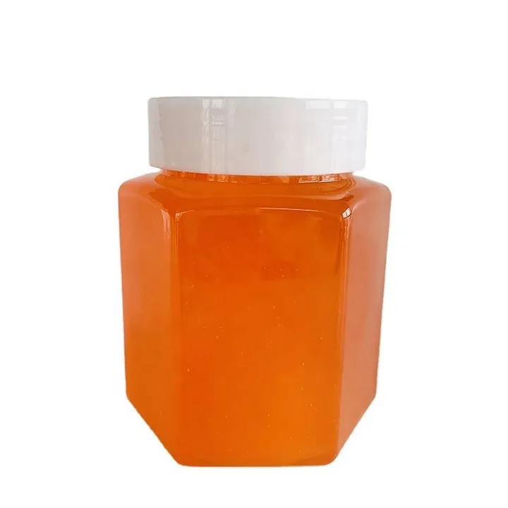 Hexagon clear jar filled with orange honey and white screw lid