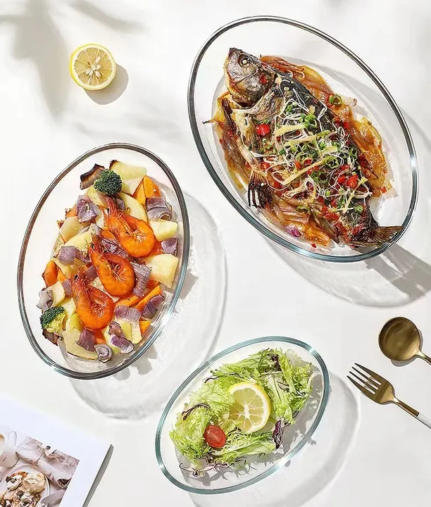 Trois plats de cuisson ovales en verre remplis de fruits de mer et de salade sur une table à manger