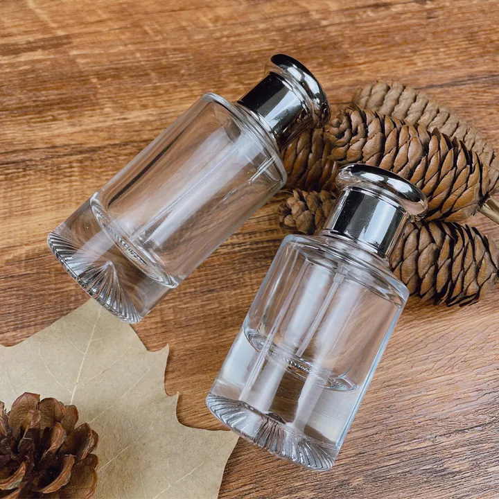 Dos frascos de perfume cilíndricos transparentes con tapones de disco plateados