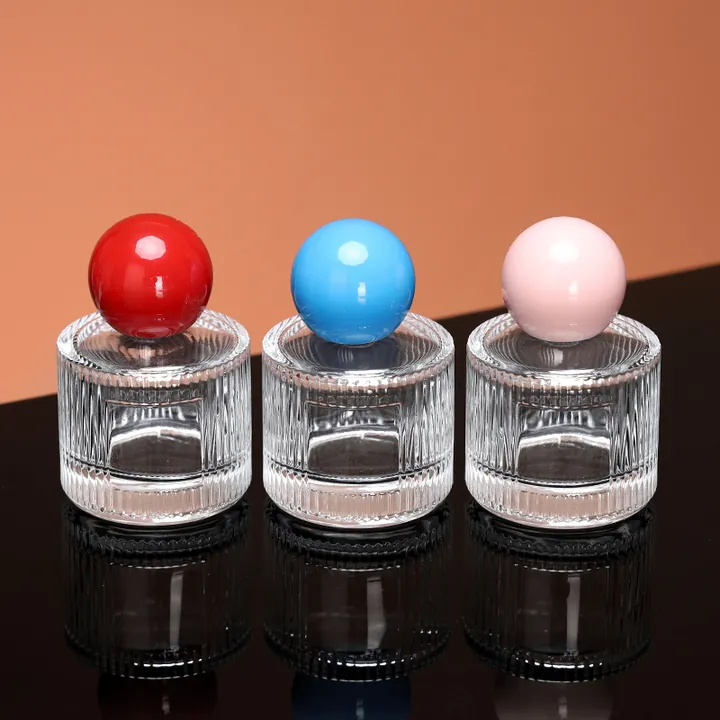 Three round perfume oil bottles with colored ball caps
