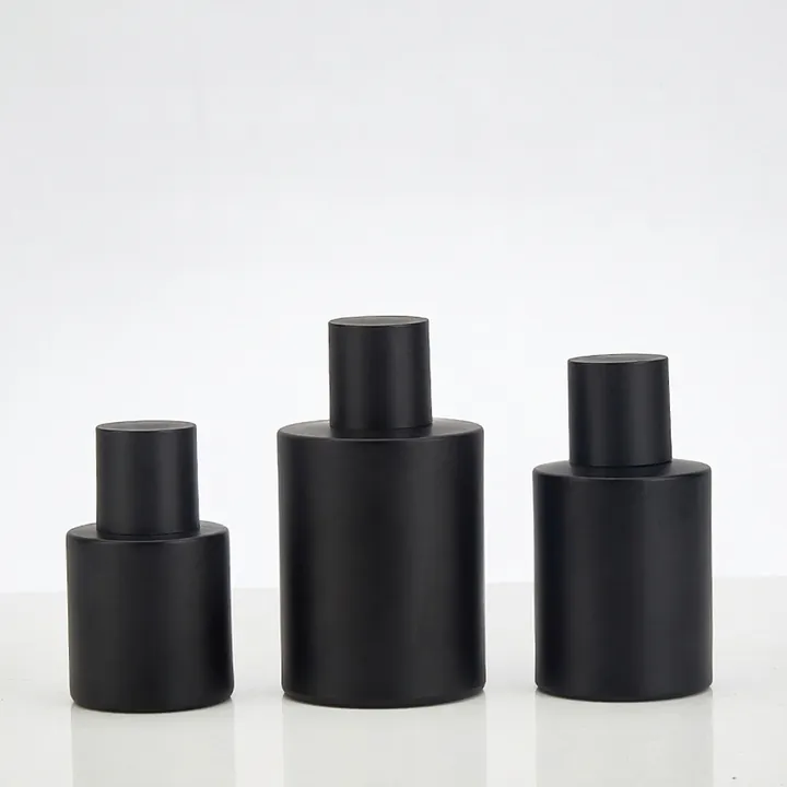 Three black cylindrical perfume oil bottles in different sizes