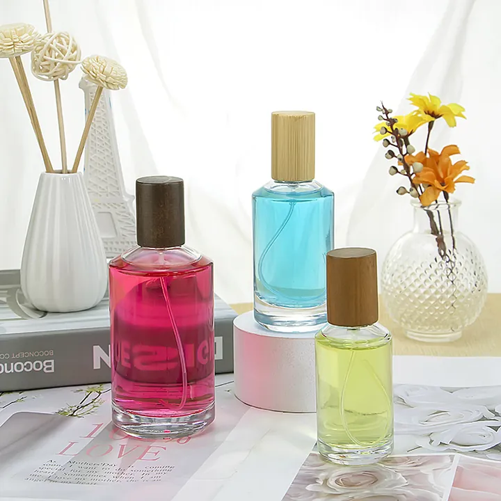 Three colored cylindrical perfume oil spray bottles with wood caps