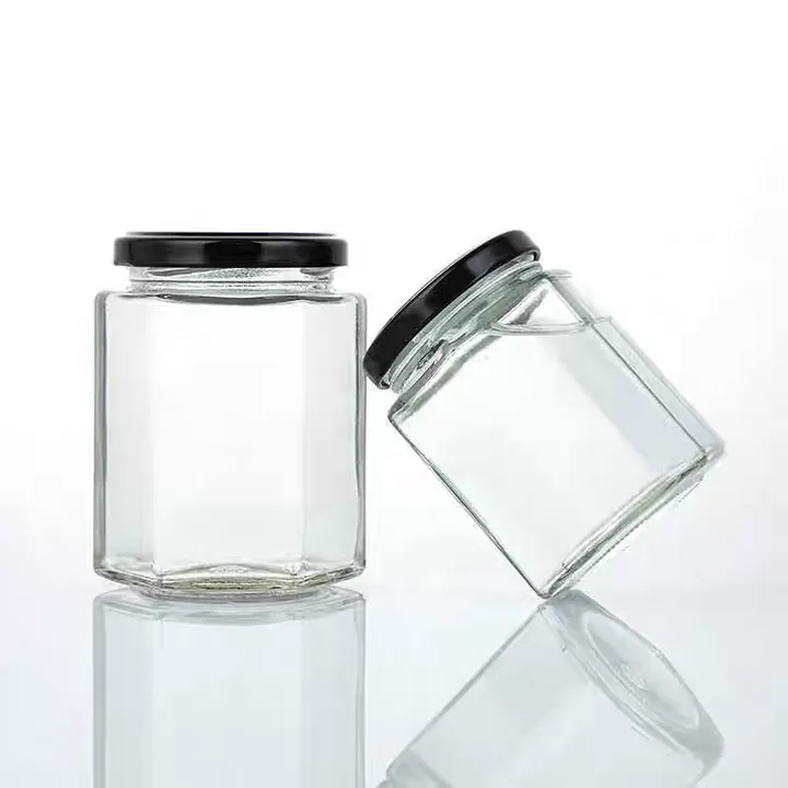 Two clear rounded square glass jars with black screw lids