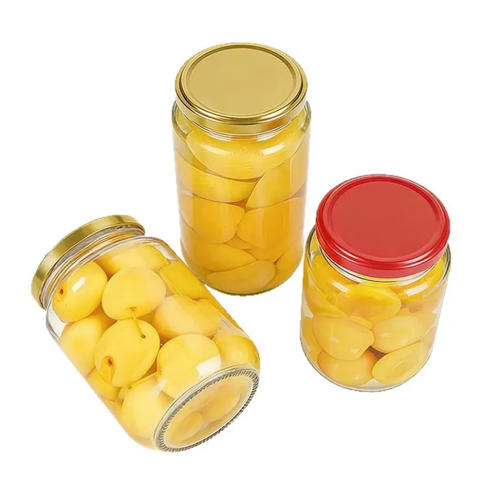 Three round glass jars filled with yellow pickled food and metal lids