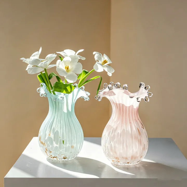Rosa und grüne Glasvasen mit Rüschen und Blumen