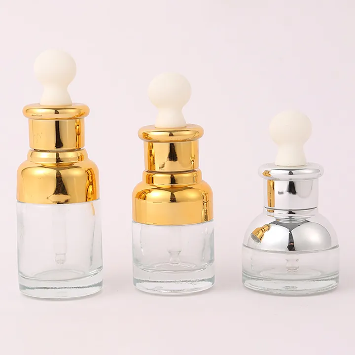 Three clear round serum dropper bottles with gold and silver caps