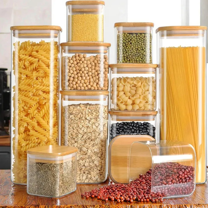 Square glass food storage jars with bamboo lids filled with pasta beans and grains