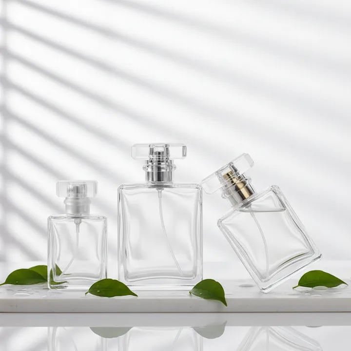 Three square clear glass spray bottles in a staged product scene