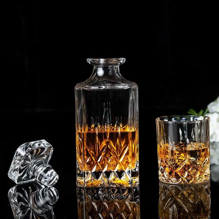 Une carafe à whisky en cristal taillé et des verres sur fond noir