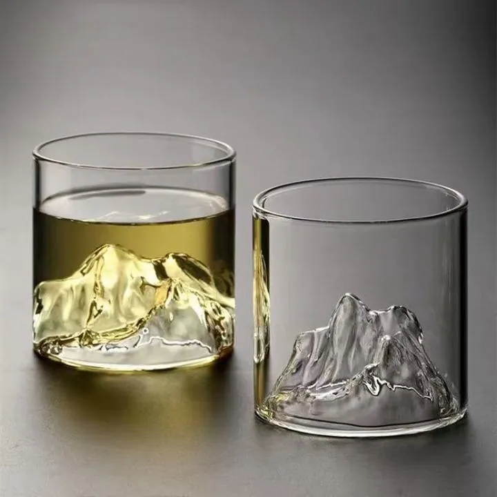Two mountain base whiskey glasses with one filled and one empty