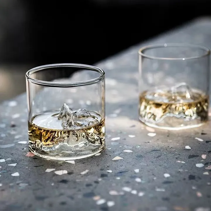 Two mountain base whiskey glasses with drinks in a tabletop scene