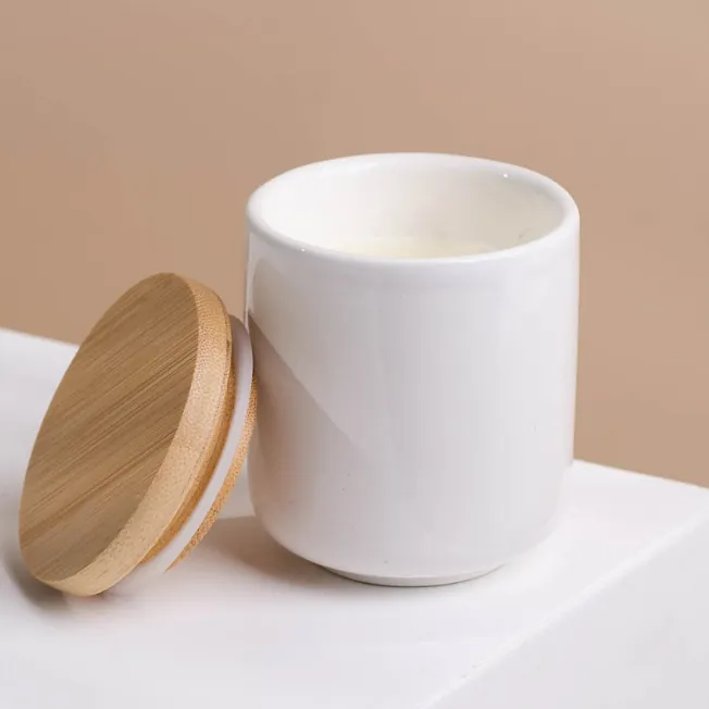 Glossy white ceramic candle jar with bamboo lid beside it