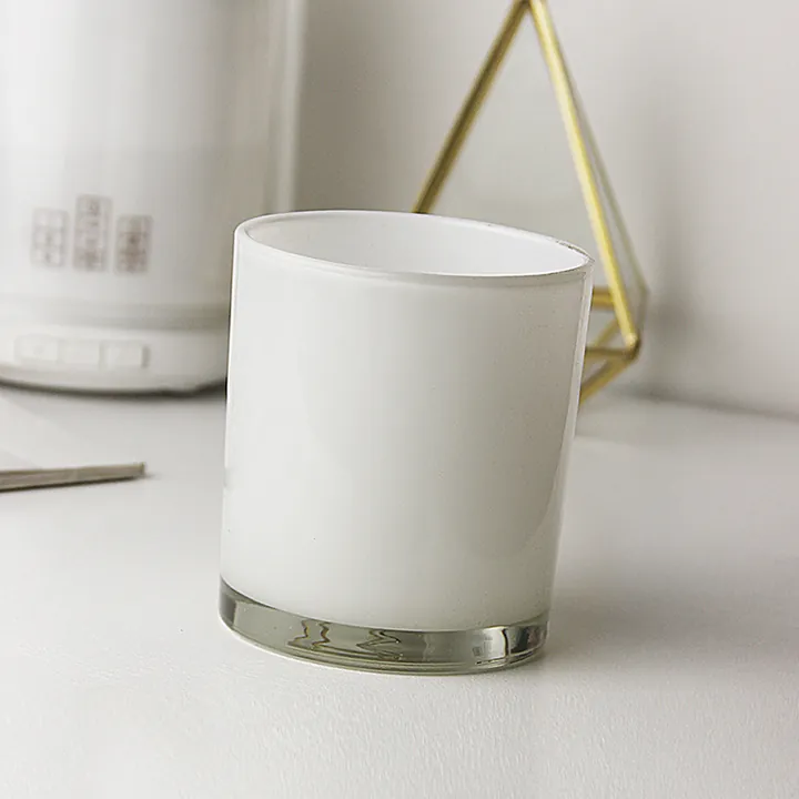 White frosted glass candle jar displayed on a table with decorative background items