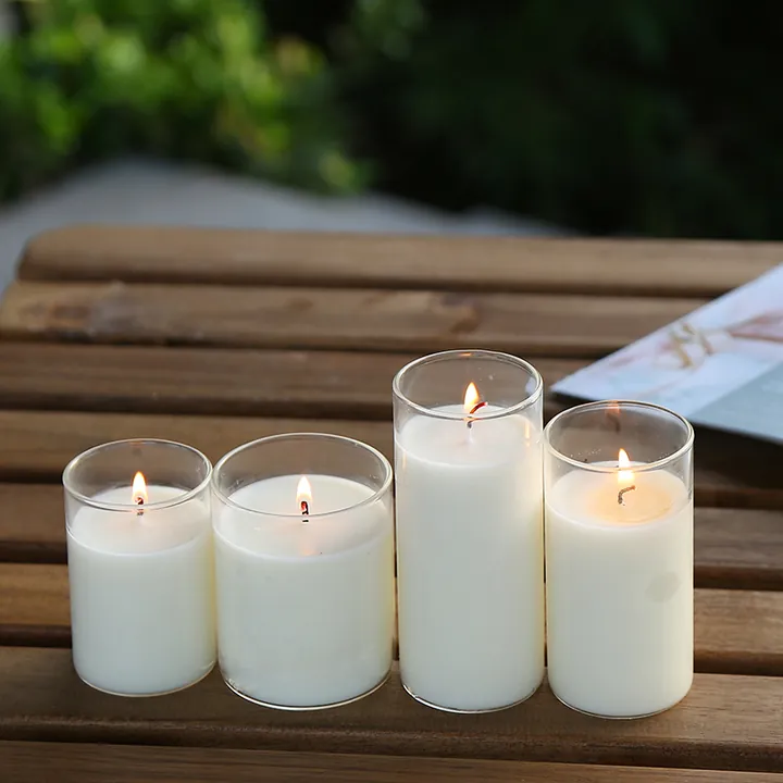 Lit white candle jars on an outdoor wooden table