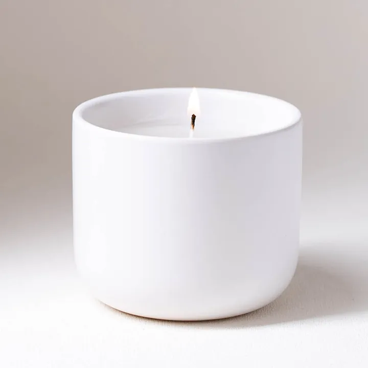 Wide white ceramic candle jar with white candle inside