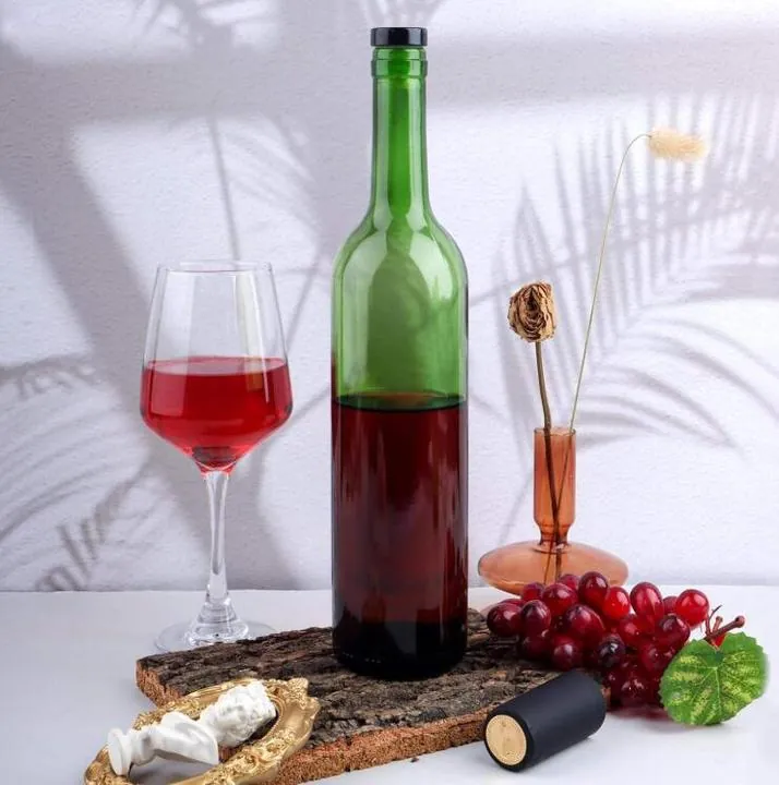 Green glass wine bottle with wine glasses, grapes and corks on a table