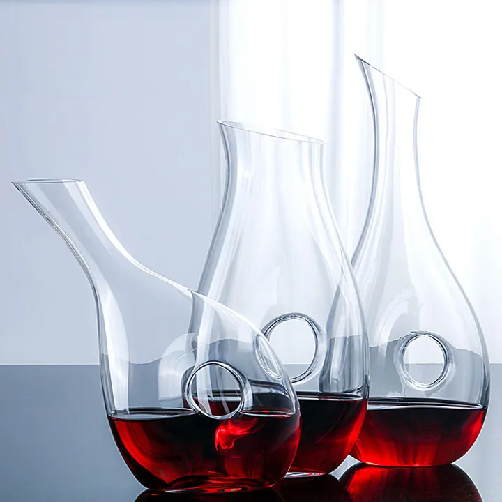 Cuatro decantadores de vino de cristal con estructuras circulares en forma de anillo expuestos juntos