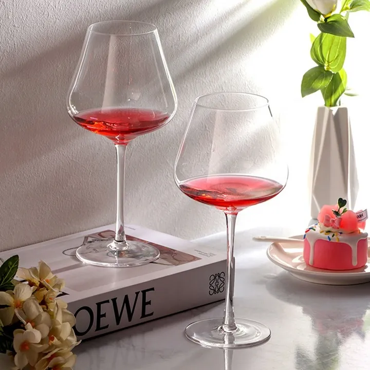 Deux grands verres à vin bordeaux transparents posés sur une table claire