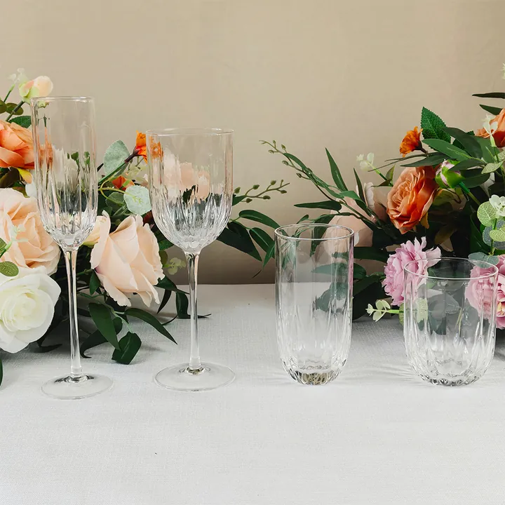 Quatre verres à vin transparents gravés, disposés sur une table décorée de motifs floraux