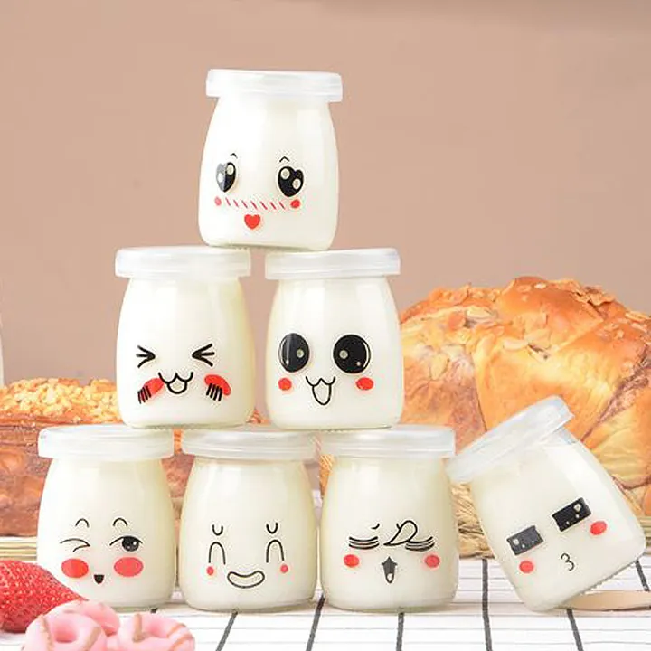 Round yoghurt glass jars with white lids and face patterns