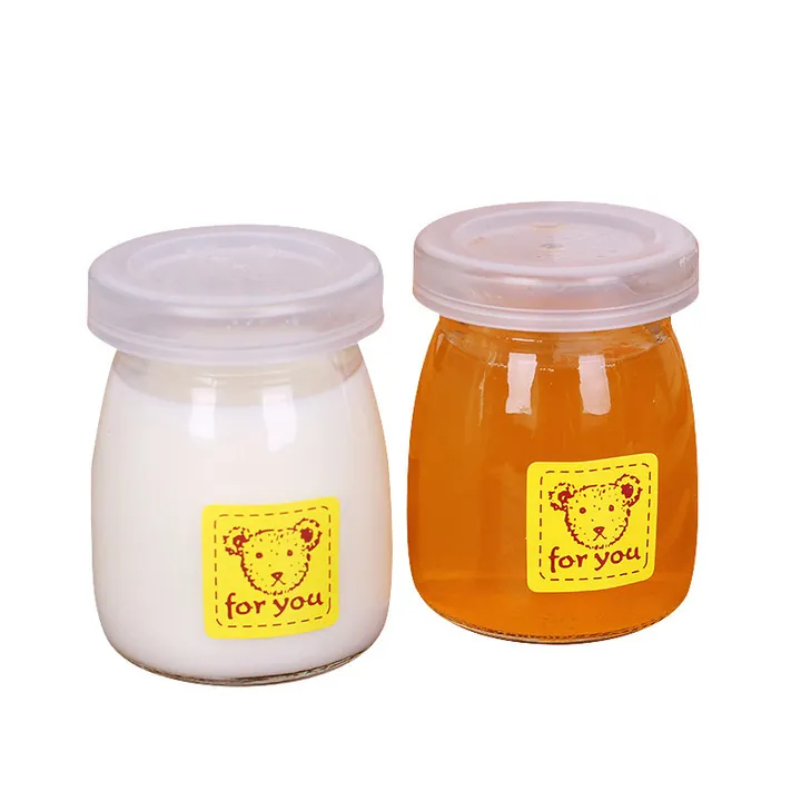 Two glass yogurt jars with plastic lids and different colored drinks