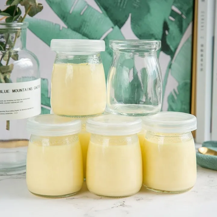 Glass yogurt jars with plastic lids filled with yogurt in a lifestyle scene